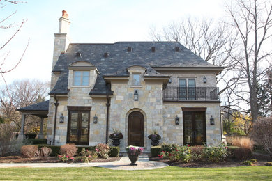 Mid-sized traditional beige two-story stone house exterior idea in Chicago with a hip roof and a shingle roof