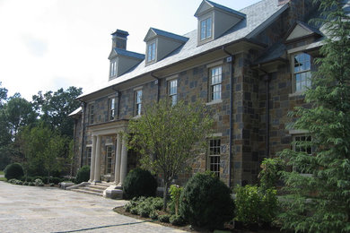 На фото: большой, трехэтажный, коричневый дом в классическом стиле с облицовкой из камня с