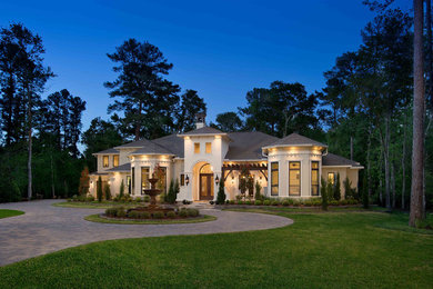 Inspiration for a large transitional beige two-story stucco house exterior remodel in Houston with a hip roof and a shingle roof