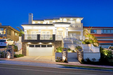 Huge transitional yellow three-story stucco house exterior idea in Orange County with a tile roof