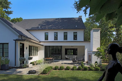 Идея дизайна: большой, двухэтажный, белый частный загородный дом в стиле неоклассика (современная классика) с облицовкой из цементной штукатурки, двускатной крышей и крышей из гибкой черепицы