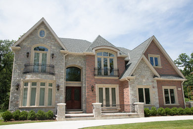 This is an example of a large and red traditional two floor brick house exterior in Chicago with a half-hip roof.