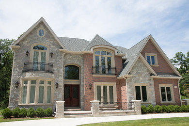 Inspiration for a large transitional red two-story brick exterior home remodel in Chicago with a clipped gable roof