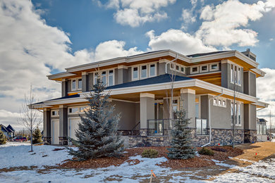Inspiration for a mid-sized transitional gray two-story stucco exterior home remodel in Calgary with a hip roof