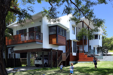 Diseño de fachada de casa blanca tropical de tamaño medio de dos plantas con revestimientos combinados, tejado plano y tejado de metal