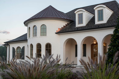Imagen de fachada de casa blanca ecléctica grande de dos plantas con revestimiento de ladrillo, tejado a cuatro aguas y tejado de varios materiales