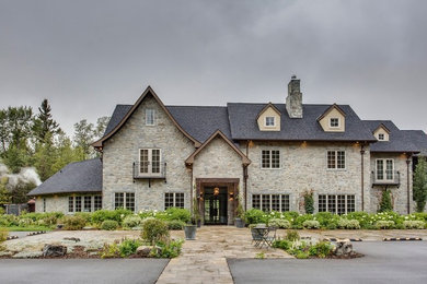 Large farmhouse multicolored three-story stone exterior home idea in Calgary with a shingle roof