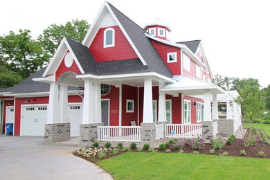 Ejemplo de fachada de casa roja de estilo americano de tamaño medio de dos plantas con revestimiento de madera, tejado a dos aguas y tejado de teja de madera