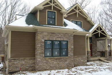 Modelo de fachada de casa beige de estilo americano de tamaño medio de dos plantas con revestimiento de aglomerado de cemento, tejado a dos aguas y tejado de teja de madera