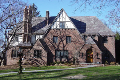 Aménagement d'une grande façade de maison rouge classique en brique à un étage avec un toit à quatre pans.