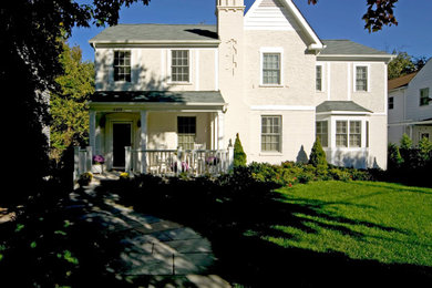 Diseño de fachada de casa beige clásica de tamaño medio de dos plantas con revestimiento de estuco, tejado a cuatro aguas y tejado de teja de madera