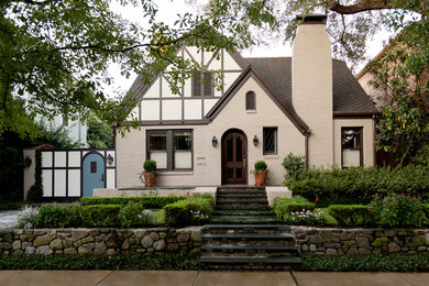 Cette image montre une façade de maison beige traditionnelle à un étage avec un revêtement mixte et un toit à deux pans.