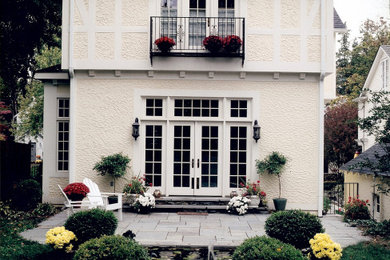 Imagen de fachada de casa beige de tamaño medio de dos plantas con revestimiento de estuco, tejado a dos aguas y tejado de teja de madera