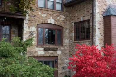 Huge elegant red three-story brick house exterior photo in Milwaukee with a clipped gable roof and a shingle roof