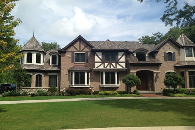 Inspiration for a large timeless brown two-story brick house exterior remodel in Chicago with a hip roof and a shingle roof