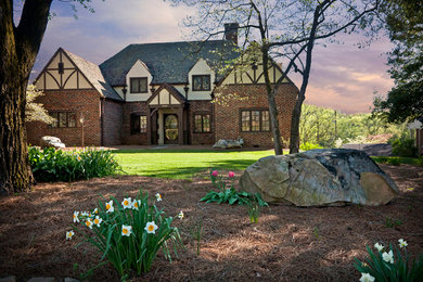 Large traditional beige three-story brick exterior home idea in Other with a hip roof