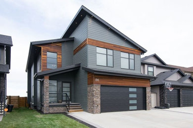 Cette photo montre une façade de maison grise moderne de taille moyenne et à un étage avec un revêtement mixte et un toit en appentis.