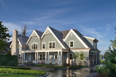 Immagine della villa grande blu classica a due piani con rivestimento in legno, tetto a capanna e copertura a scandole