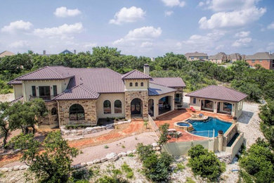 Example of a large southwest white two-story stone exterior home design in Austin with a shingle roof
