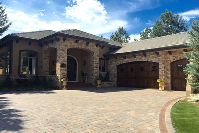 Inspiration for a huge rustic beige one-story stone house exterior remodel in Denver with a hip roof and a tile roof