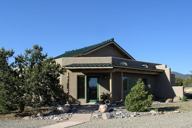 This is an example of a medium sized and brown eclectic bungalow render house exterior in Albuquerque with a pitched roof.