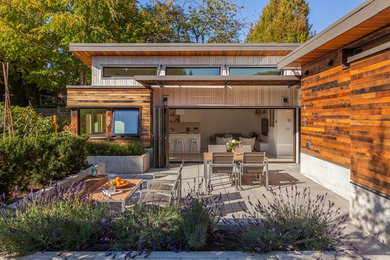Imagen de fachada de casa marrón minimalista grande de dos plantas con revestimiento de madera, tejado plano y tejado de metal