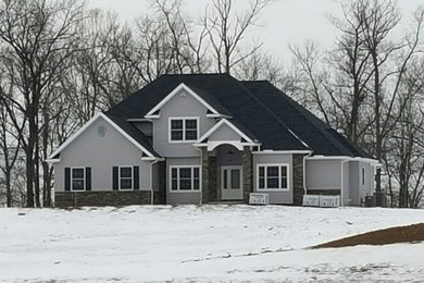 Imagen de fachada de casa gris de estilo americano grande de dos plantas con revestimientos combinados, tejado a dos aguas y tejado de teja de madera