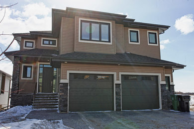 This is an example of a large and brown contemporary two floor house exterior in Edmonton with vinyl cladding.
