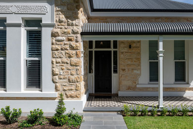 Modelo de fachada de casa beige tradicional de tamaño medio de una planta con revestimiento de piedra, tejado plano y tejado de metal