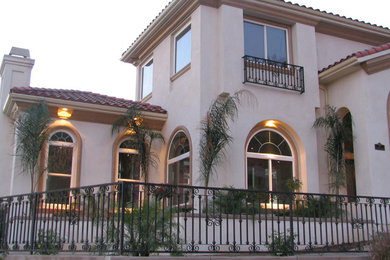 Large tuscan beige two-story stucco exterior home photo in Los Angeles with a hip roof