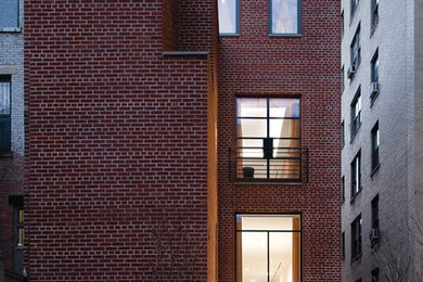 Esempio della facciata di una casa contemporanea a tre piani con rivestimento in mattoni