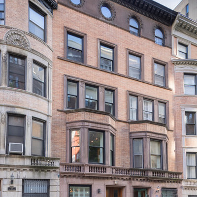 Example of a large classic red three-story brick exterior home design in New York with a shingle roof