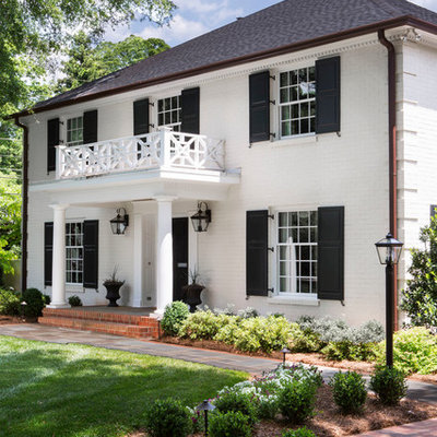 Example of a classic white two-story brick exterior home design in Charlotte with a hip roof