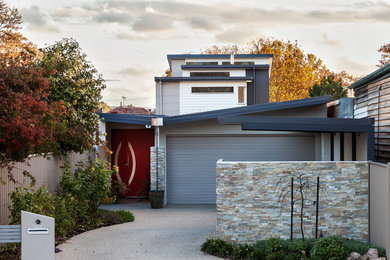 Cette photo montre une grande façade de maison multicolore tendance à deux étages et plus avec un revêtement mixte, un toit plat et un toit en métal.