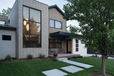 Imagen de fachada de casa blanca contemporánea de tamaño medio de dos plantas con revestimiento de ladrillo, tejado a dos aguas y tejado de metal