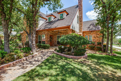 Inspiration for a mid-sized timeless beige two-story brick exterior home remodel in Dallas with a clipped gable roof