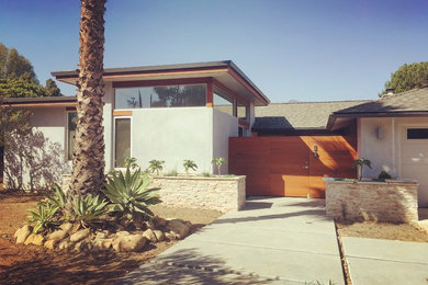Cette image montre une façade de maison grise minimaliste en stuc de taille moyenne et de plain-pied avec un toit plat et un toit mixte.