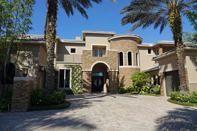 Large trendy beige two-story mixed siding exterior home photo in Miami with a tile roof