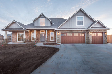 Example of a large arts and crafts gray two-story brick exterior home design in Oklahoma City with a hip roof
