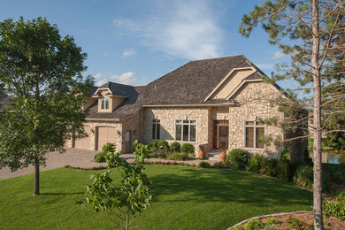 Inspiration for a large and beige classic bungalow house exterior in Minneapolis with stone cladding and a hip roof.