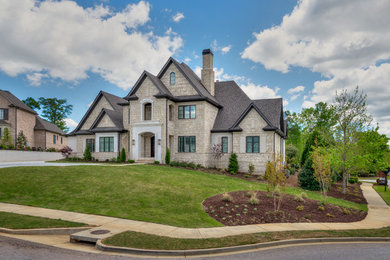 Inspiration for a large transitional beige two-story stone exterior home remodel in Other with a shingle roof