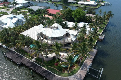 Huge beach style beige two-story stucco exterior home photo in Miami with a metal roof