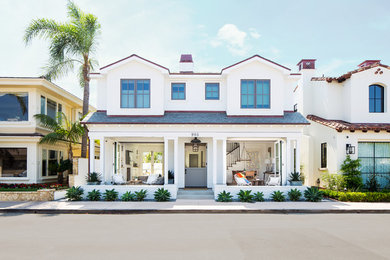 Example of a beach style white two-story house exterior design in Orange County with a shingle roof