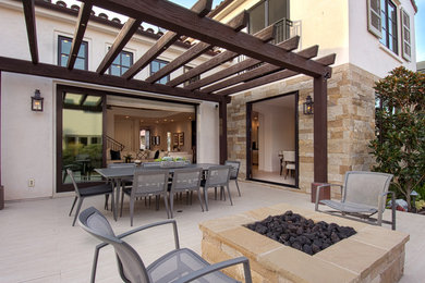 Immagine di un patio o portico design dietro casa con un focolare e una pergola