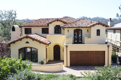 Modelo de fachada de casa beige mediterránea grande de tres plantas con revestimiento de estuco, tejado a cuatro aguas y tejado de teja de barro