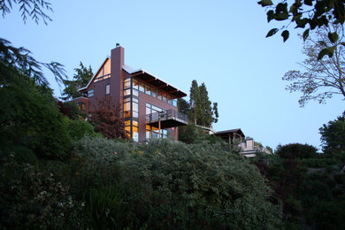 Пример оригинального дизайна: трехэтажный, коричневый частный загородный дом среднего размера в современном стиле с облицовкой из ЦСП, двускатной крышей и металлической крышей