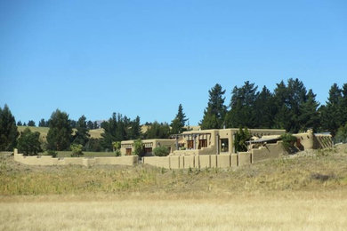 Example of a huge brown one-story adobe exterior home design in Christchurch