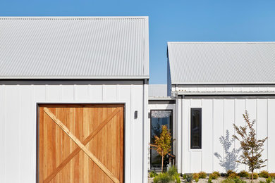 Свежая идея для дизайна: двухэтажный, белый частный загородный дом среднего размера в стиле кантри с облицовкой из бетона, двускатной крышей и металлической крышей - отличное фото интерьера