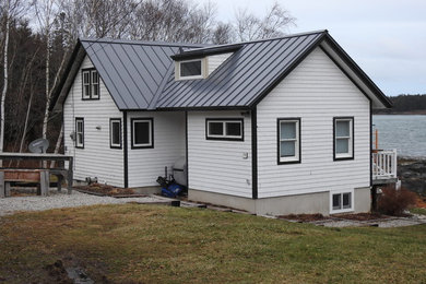 Example of a white one-story house exterior design in Portland Maine with a metal roof