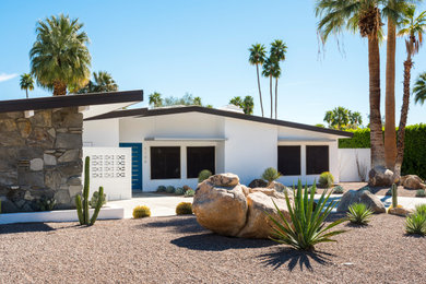Example of a large 1960s white one-story stucco exterior home design in Other with a mixed material roof